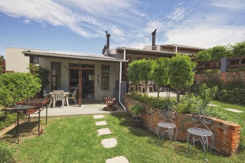 a house with a yard with chairs and a patio at A Hilltop Country Retreat in Swellendam