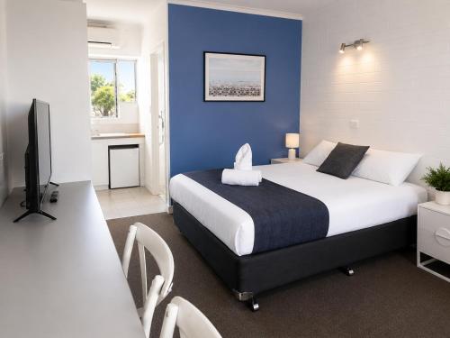 a bedroom with a large bed with a blue wall at Forster Motor Inn in Forster