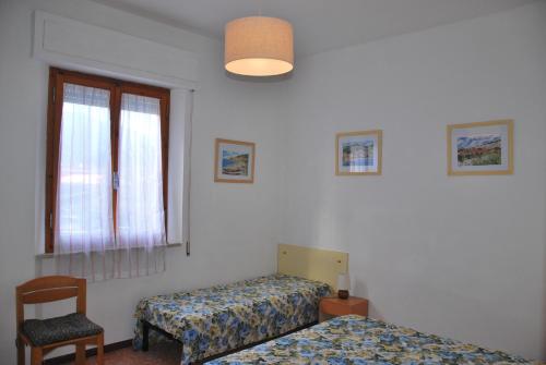 a bedroom with two beds and a chair and a window at Appartamenti Mare in Marina di Campo