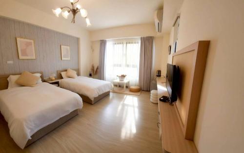 ein Hotelzimmer mit zwei Betten und einem Flachbildfernseher in der Unterkunft PiR2 House in Tainan