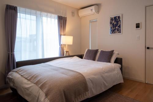 a bedroom with a large bed and a window at Furano Ezo Murasaki B in Furano