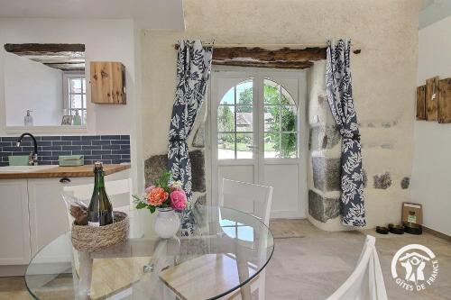 a kitchen and dining room with a glass table at Le murmure des oiseaux in Plussulien