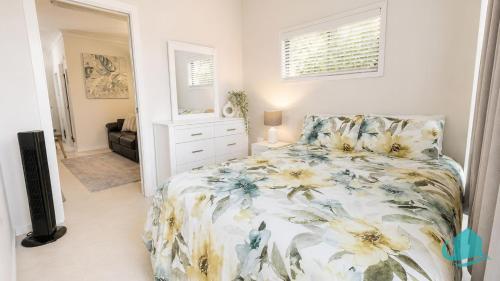 a bedroom with a bed with a floral bedspread at Coastal Hideaway at Pelican in Pelican Flat