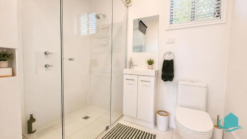 a white bathroom with a shower and a toilet at Coastal Hideaway at Pelican in Pelican Flat
