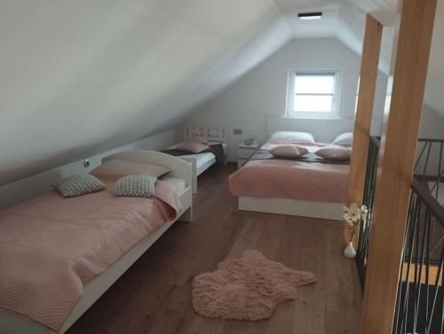 a attic bedroom with two beds and a window at Počitniška hiša Maja v naravi in Planina pri Sevnici
