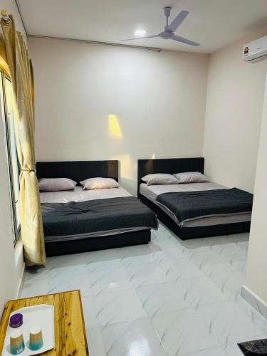 a bedroom with two beds and a coffee table at Triple S Homestay Bachok in Bachok