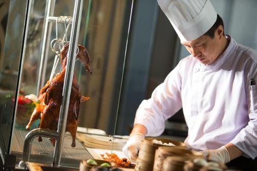 a chef preparing food in a restaurant kitchen at InterContinental Bandung Dago Pakar by IHG in Bandung