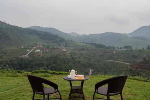 two chairs and a table with a tea set on top of a hill at Estate Bungalow with Waterfall, Mountain & Valley Views in Kotagiri