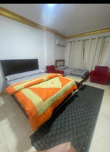 a bedroom with a bed with an orange comforter at Pyramids Heritage suites in Ghaţāţī