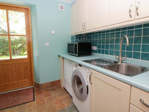a kitchen with a sink and a washing machine at Bryn Isaf in Ystrad Meurig