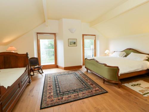 a bedroom with two beds and a rug at Bryn Isaf in Ystrad Meurig