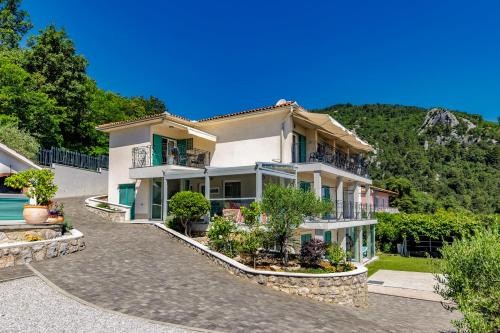 a large white house with trees and a mountain at Beachside Villa Mia Apartments in Medveja