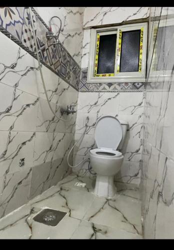 a bathroom with a white toilet and a window at Pyramids Heritage suites in Ghaţāţī