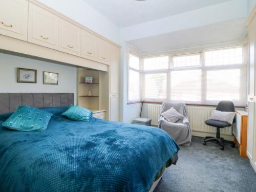 a bedroom with a blue bed and two chairs at Gwynfa in Colwyn Bay