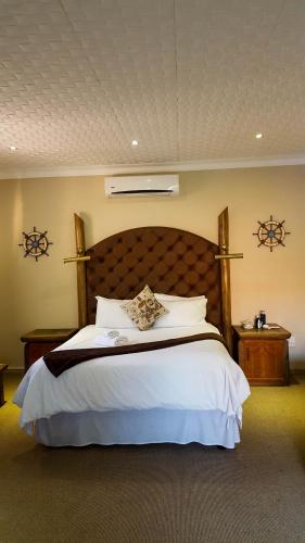 a bedroom with a large bed with white sheets and pillows at Aark Guest Lodge in Vanderbijlpark
