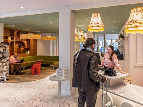 a man and a woman standing at a counter in a store at ibis Styles Metz Centre in Metz