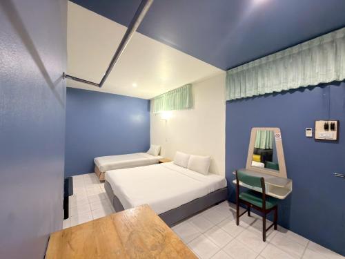 a bedroom with a bed and a table and a chair at โรงแรม วี เฮาส์ ณ คอน in Nakhon Si Thammarat
