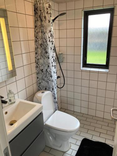 a bathroom with a toilet and a sink and a window at Cozy Cottage Close To The Beach in Bogense