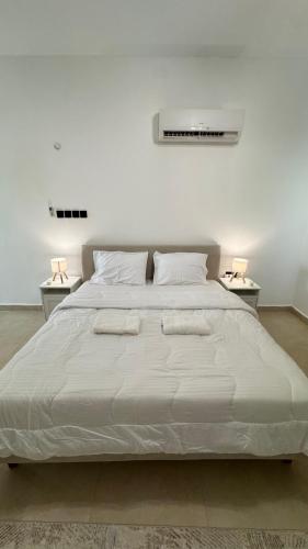 a white bedroom with a large bed with two tables at The Inn Salalah in Salalah
