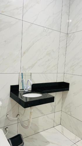 a bathroom with a sink in a marble wall at Hospedagens da Lucia in Pirenópolis