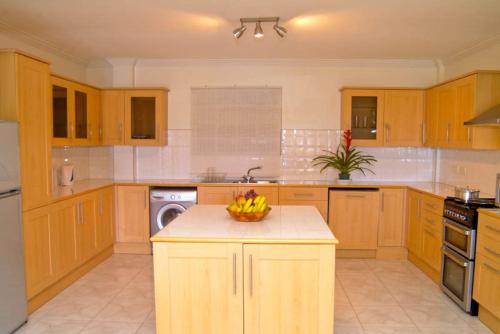 a kitchen with wooden cabinets and a bowl of fruit on a counter at Woburn Villas in Saint Georgeʼs