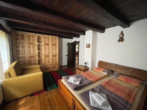 a room with two beds and a chair in it at Къща за гости Младата Баба in Apriltsi