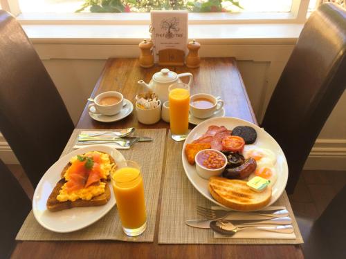 a table with two plates of breakfast foods and orange juice at The Family Tree in Whatstandwell