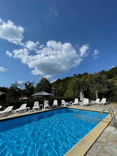 a swimming pool with chaises and chairs in a resort at Baba Stana Houses in Apriltsi