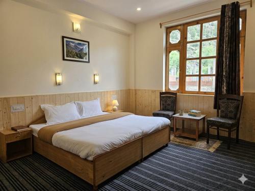 a bedroom with a bed and a chair and a window at Hotel Lady of Keylong in Kyelang