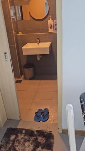 a bathroom with a sink and two pairs of shoes at Swiss belhotel apartment in Kuantan