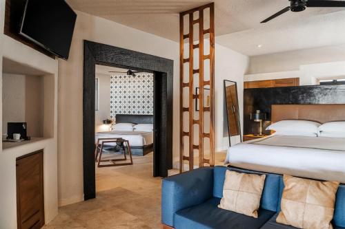 a bedroom with a large bed and a blue chair at Thompson Zihuatanejo, A Beach Resort, by Hyatt in Zihuatanejo