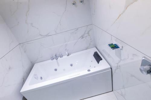 a white bath tub in a white tiled bathroom at Lumis Beach Hotel in Visakhapatnam