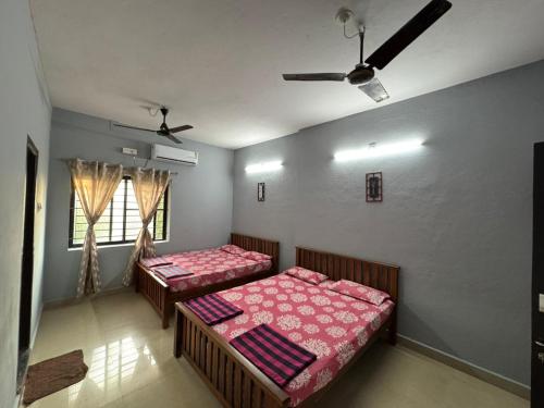 a bedroom with two beds and a window at Kenson Retreat in Mangalore