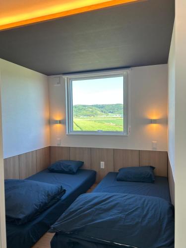 two beds in a room with a window at Villa ORAN in Nakafurano