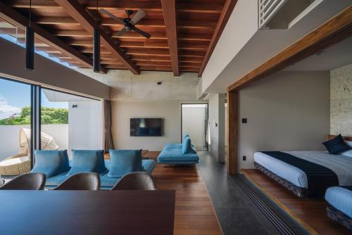 a bedroom with a bed and blue chairs at Villa Azure Mira in Miyakojima