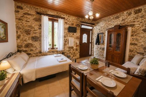 a room with a bed and a table and a couch at Pandora Stone Cottage Elos in Élos