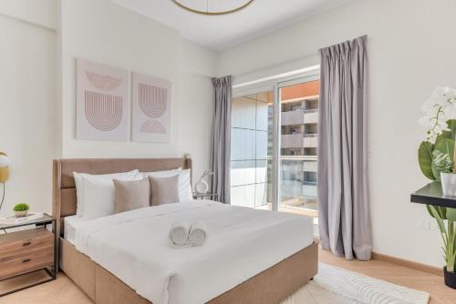 a bedroom with a bed and a large window at Stella Stays Barsha Heights in Dubai