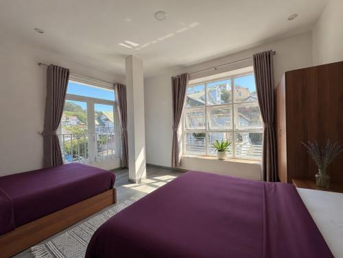 a bedroom with a purple bed and a large window at Big Home Dalat in Da Lat