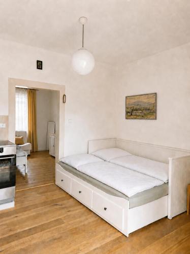 a white bed in a room with a kitchen at Domek u vína in Perná