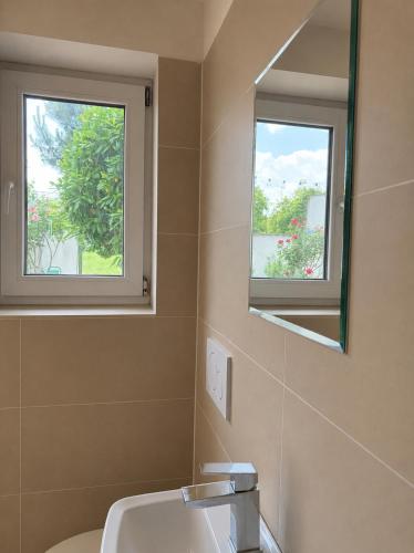 a bathroom with a sink and a mirror and two windows at Domek u vína in Perná
