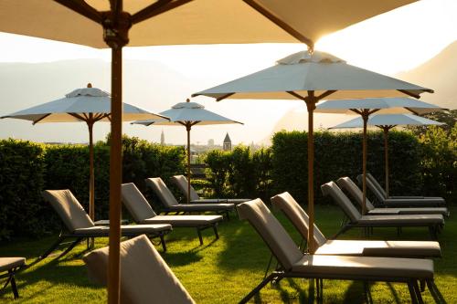 a row of chairs and umbrellas on a lawn at Hotel Magdalener Hof in Bolzano