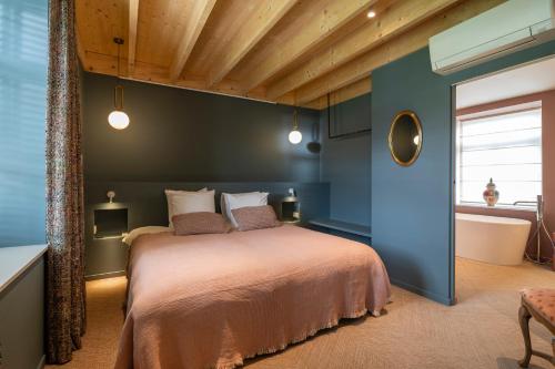 a bedroom with a bed and a blue wall at Entre Pierres et Rivière - 2 Gites avec wellness privatifs in Hotton