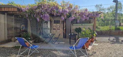 a garden with two chairs and a pergola with purple flowers at Il Mulino B&B in Rivara