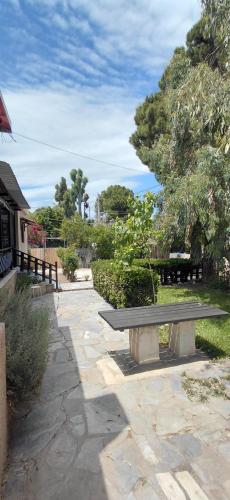 a park bench sitting on a stone walkway at Marathon Βeach Ηouse in Panayía Mesosporítissa