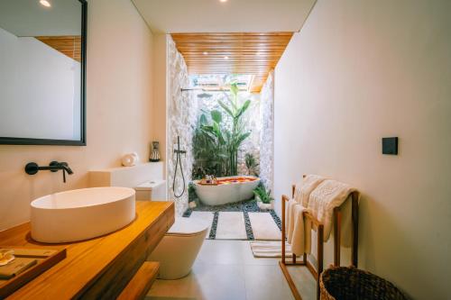 a bathroom with a tub and a sink and a toilet at Candidasa Hills in Candidasa