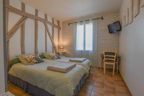a bedroom with two beds and a television in it at La louvière in Jeugny