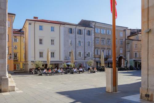 a group of buildings with people sitting in a courtyard at Neris Boutique Rooms in Muggia