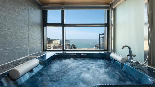 a jacuzzi tub in a room with a window at Capella Oceanview Spa Resort – Goseong in Goseong
