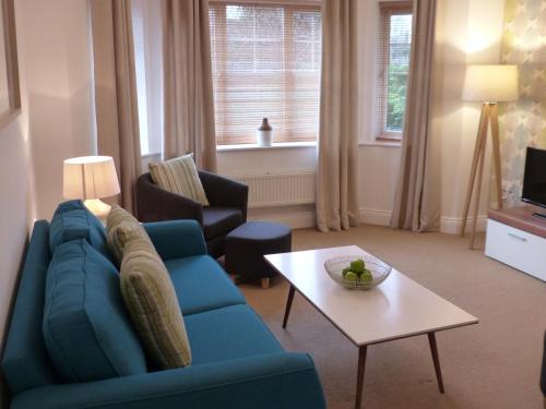 a living room with a blue couch and a table at Basingstoke Apartments - St Raphael House, City Centre Charming Apartments in Basingstoke