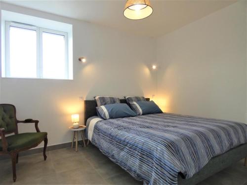 a bedroom with a bed and a chair and a window at Le clémens in Herm